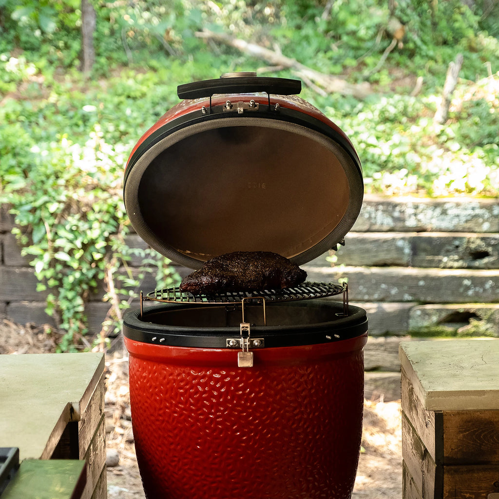 A Boston butt on the grate of an open standalone grill installed in an outdoor kitchen.
