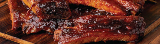 Close-up of smoked and sauced ribs on a wooden surface