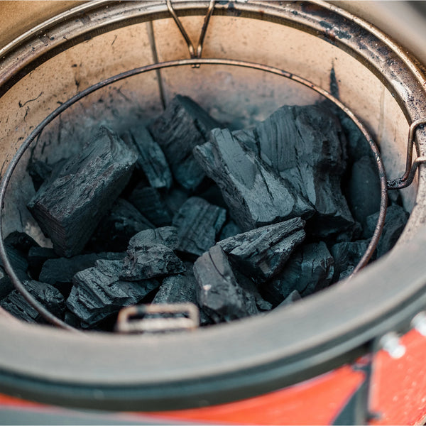 A pile of big block lump charcoal inside the firebox of a Kamado Joe grill