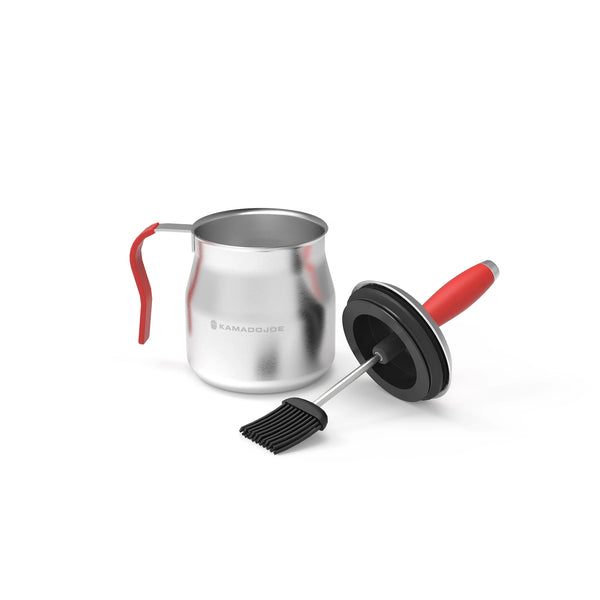 Steel basting pot with red handle sitting next to the combined brush/pot lid all against a white background.