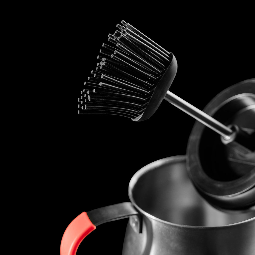 Closeup of the black silicone brush head. The seal on the lid is visible behind the brush head.
